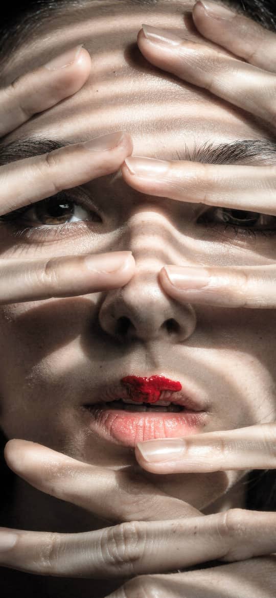 Woman's Face Hidden by Pale Hands