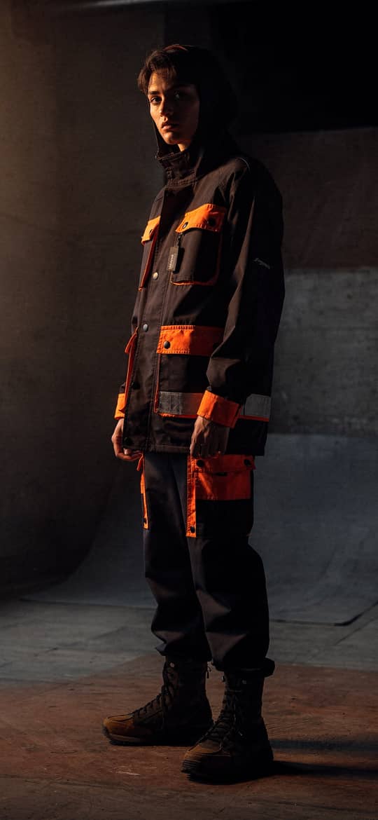 Young Man in Orange Workwear in Concrete Warehouse