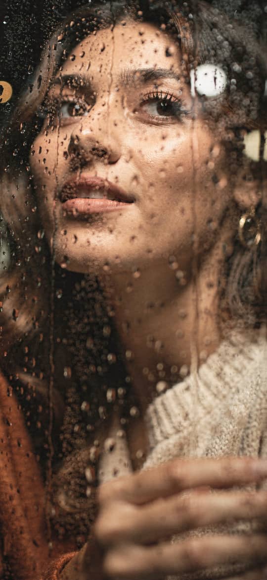 Woman Gazing Through Rainy Window Glass